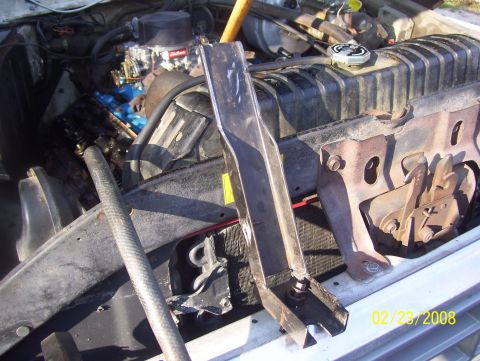 1978 Ford Bronco - The engine bay of a vehicle shows a radiator, hoses, and carburetor, with a metal bracket in the foreground.