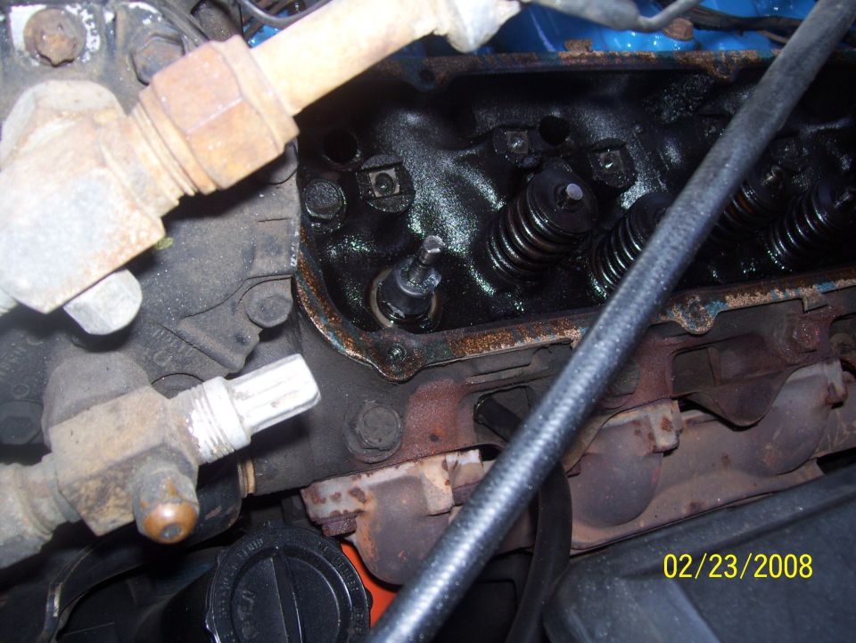 Engine valve springs and rusty exhaust manifold with visible date stamp 02/23/2008