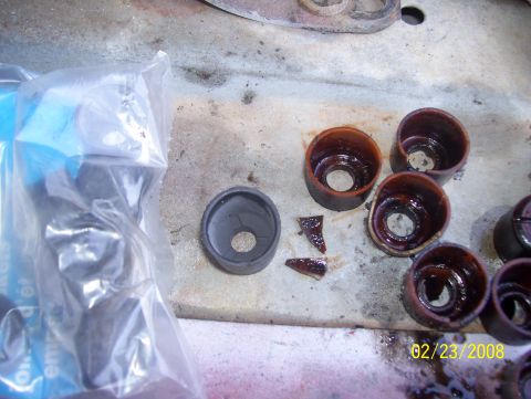 1978 Ford Bronco - Several used valve seals and some broken fragments are laid out on a surface next to a bag of new parts.