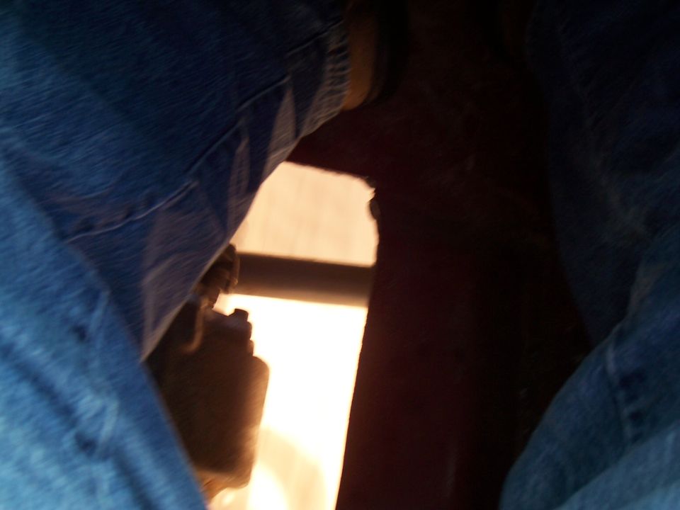 Close-up of someone's legs in jeans inside a vehicle, looking out a window