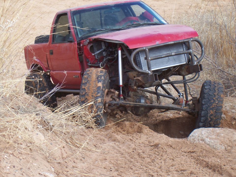 Red pickup truck with off-road modifications stuck in dirt