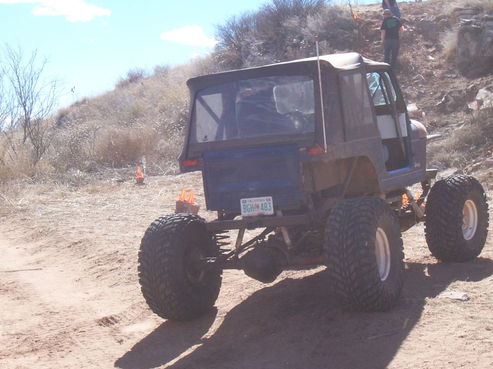 Rear view of a modified off-road vehicle with large tires and a blue license plate