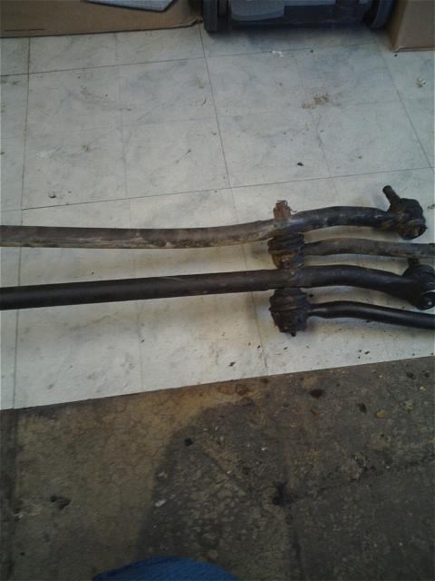 1994 Ford Bronco - Several automotive steering linkage components are shown laid out on a workshop floor.