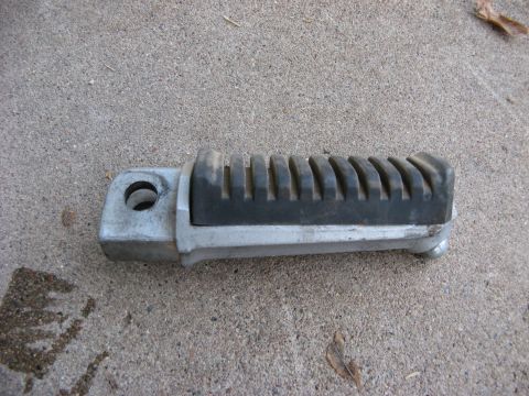 2007 Kawasaki Ninja - A single motorcycle foot peg, likely a replacement part, rests on a concrete surface.