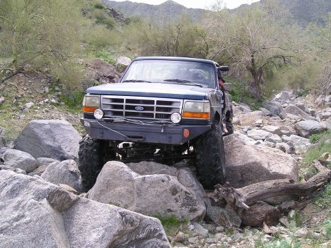 1986 Toyota Hilux - Ford Bronco tackling a challenging rocky terrain, its off-road capabilities.