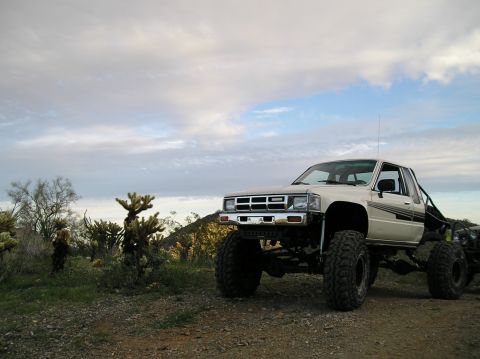 1986 Toyota Hilux - A modified pickup truck sits in a dry, desert environment under a cloudy sky.