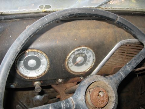 1952 Ford Panel Van - The dashboard of an old vehicle shows a speedometer, fuel gauge, and battery indicator, with visible rust and significant wear.