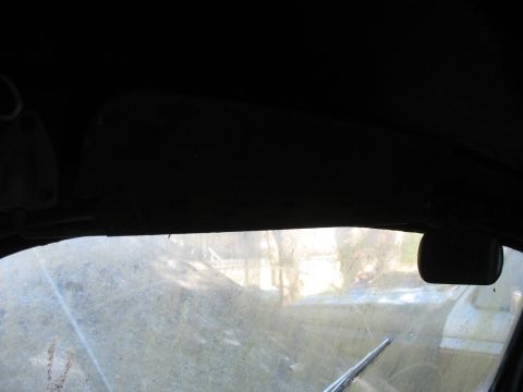 1952 Ford Panel Van - Interior view through a dusty windshield reveals a sun visor and side mirror, with another vehicle glimpsed outside.