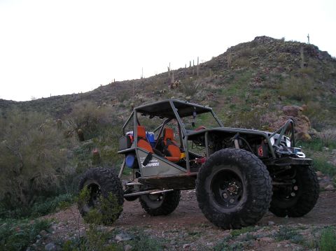 1986 Toyota Hilux - Custom off-road buggy with oversized tires and roll cage sits on a desert trail.