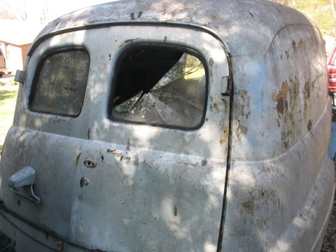 1952 Ford Panel Van - The rear of a light blue panel van shows significant rust and a shattered window.