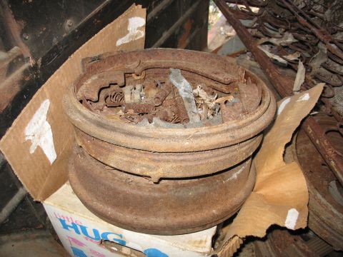1952 Ford Panel Van - Rusted brake drums and vehicle parts are piled inside a cardboard box, suggesting a collection of old automotive components.