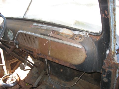 1952 Ford Panel Van - Interior view of a 1952 Ford Panel Van dashboard, showing the Ford emblem and rusted controls.