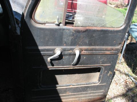 1952 Ford Panel Van - Interior view of a 1952 Ford Panel Van door, two chrome door handles and a cracked window.