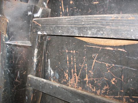 1952 Ford Panel Van - Close-up of a vintage panel van's interior body side, showing black-painted sheet metal heavily scratched to bare rusty steel with horizont…