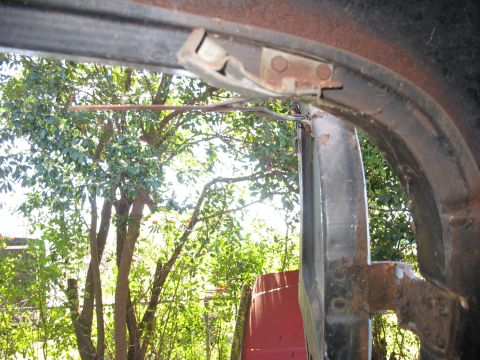 1952 Ford Panel Van - Close-up from inside a stripped vintage cab looking out through the empty windshield opening, showing the surface-rusted upper windshield f…