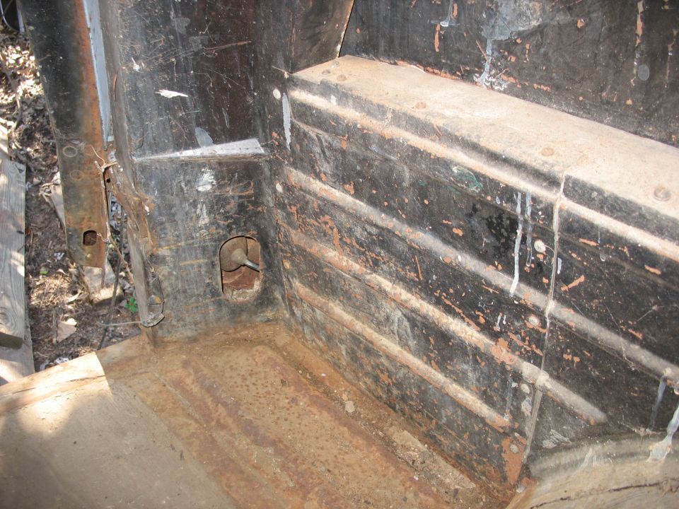Rusty stripped interior of a vehicle body with ribbed panel, peeling paint and dirt