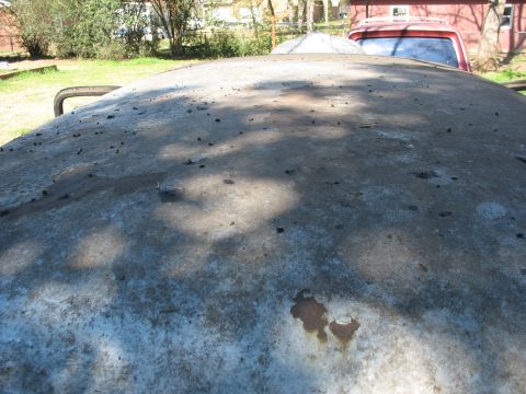 1952 Ford Panel Van - Looking along the stripped bare-metal roof of an old vehicle sitting outdoors, the surface mottled with sanding marks, primer residue and s…