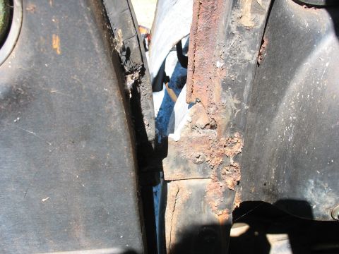 1952 Ford Panel Van - Close-up of heavy surface rust and flaking black paint on a vintage vehicle's door jamb and body pillar, with an open door panel at left. C…