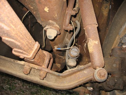 1952 Ford Panel Van - Close-up of severely rusted undercarriage suspension, steering linkage and frayed wiring with a blue wire connector.