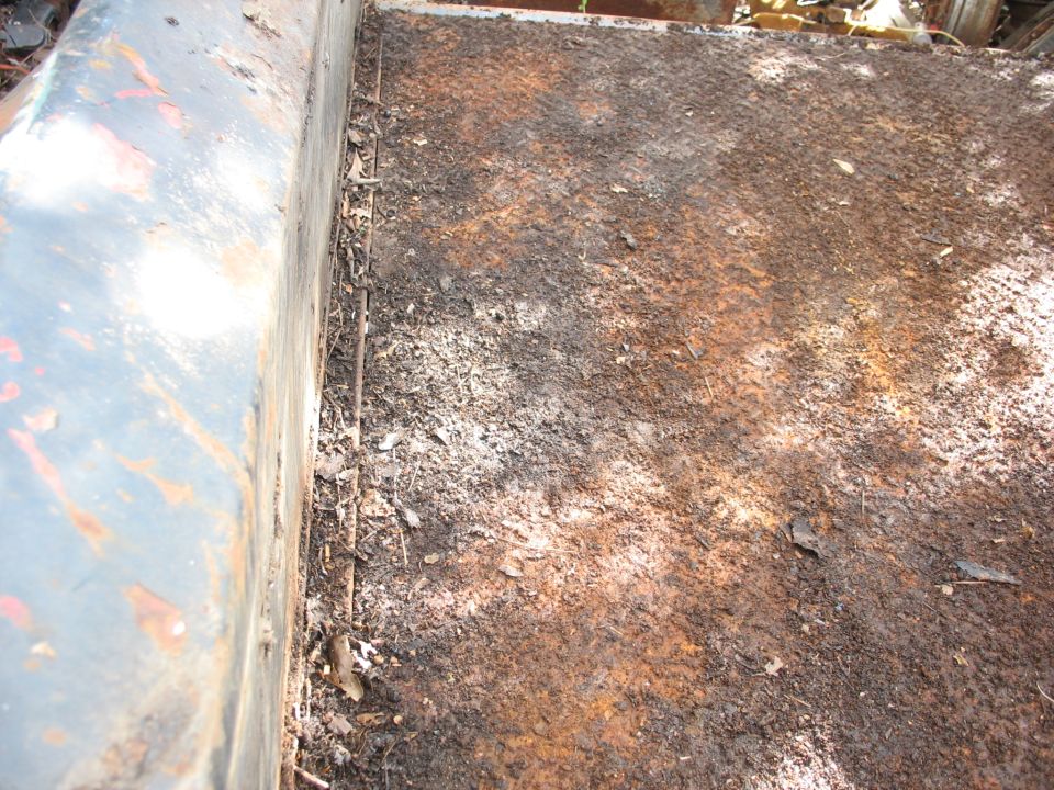 Rusty diamond plate truck bed with debris and a metal side wall