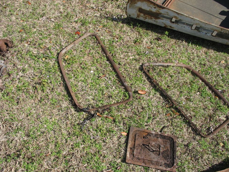 Two metal frames and a rectangular plate with a handle, lying on grass