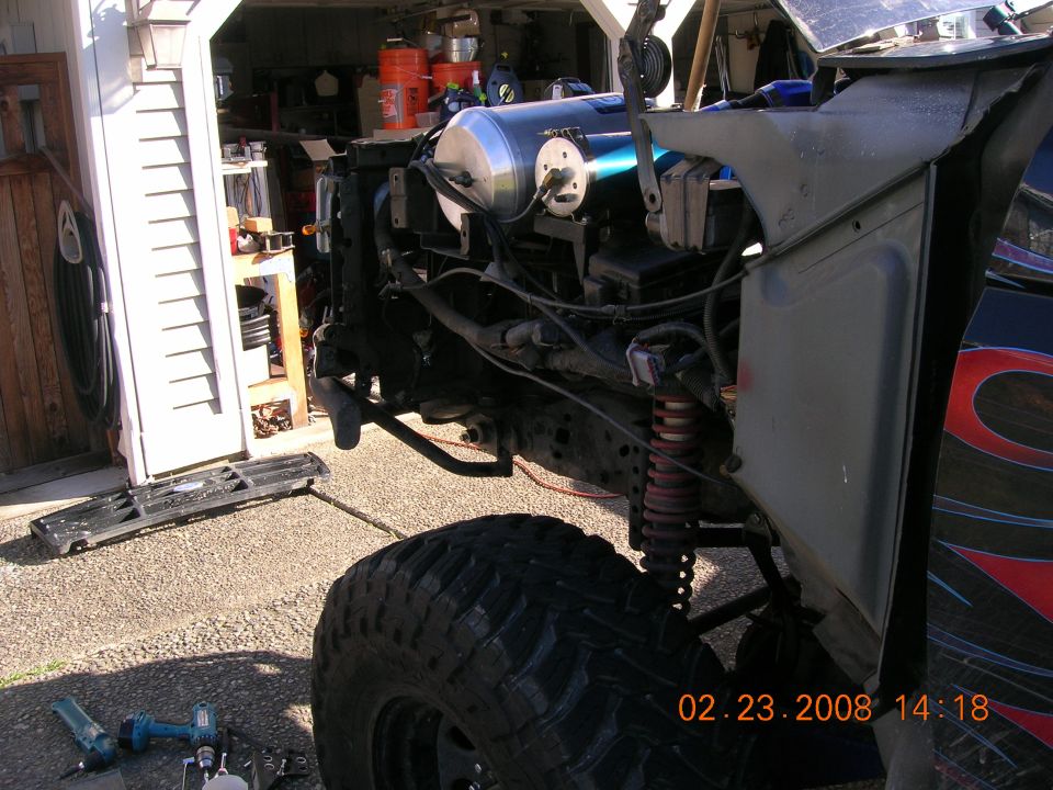 Lifted 4x4 with front clip removed showing engine bay, air tank and red coil-over shock