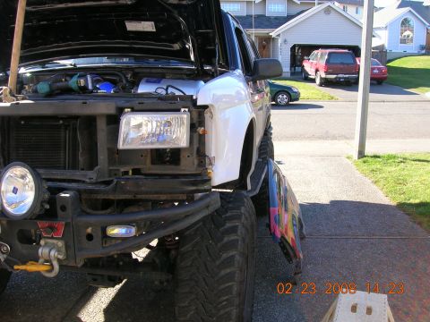 1996 Ford Bronco - SUV undergoing maintenance, with a detached fender and other vehicles in the driveway.