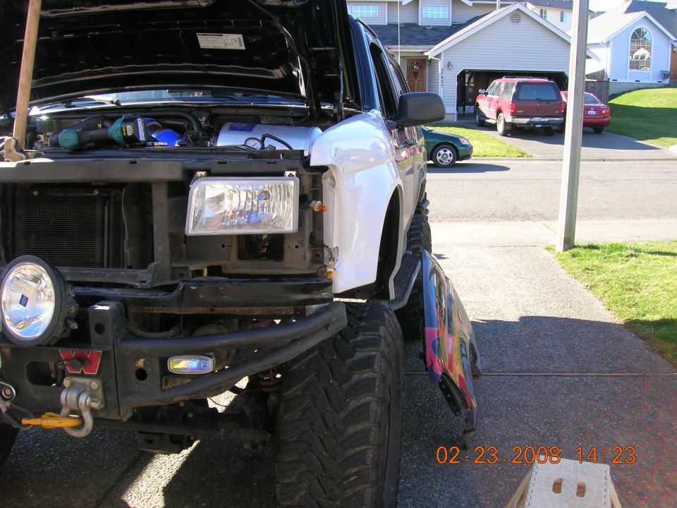 Lifted black and white Ford truck with grille and fender removed, Warn winch bumper