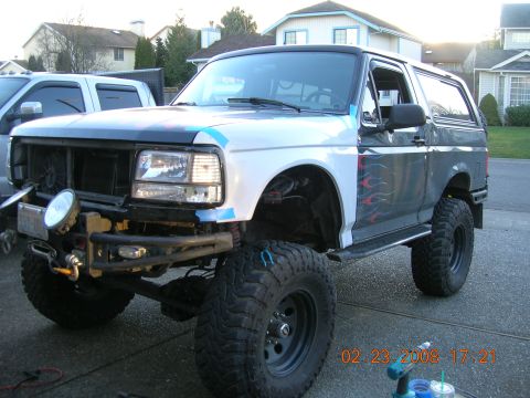 1996 Ford Bronco - A modified Ford Bronco with flame decals and a white front fender sits in a driveway.