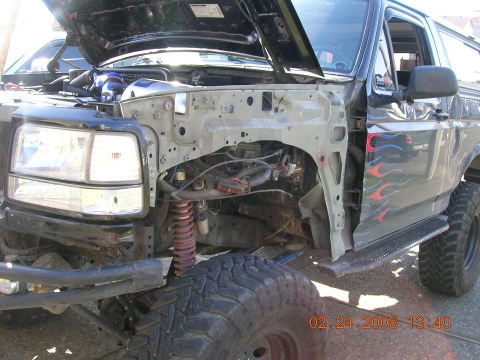 Lifted black Bronco with flames, front fender removed showing coil spring and axle