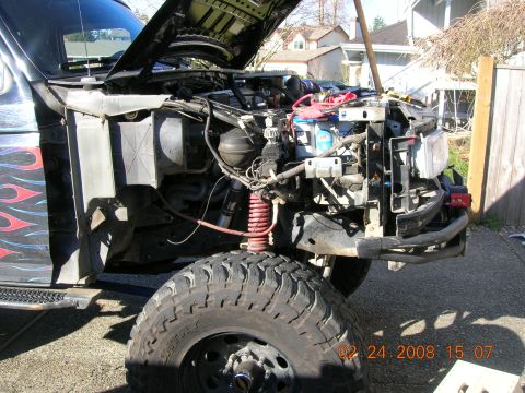 1996 Ford Bronco - Disassembled truck front end with engine exposed, suspension visible, and flame graphics on fender.