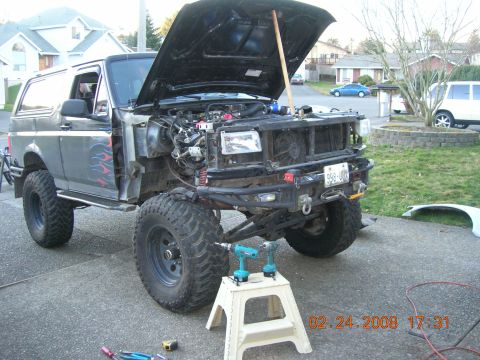1996 Ford Bronco - The front of a Ford Bronco is disassembled, showing the engine and suspension components. Tools are laid out nearby.