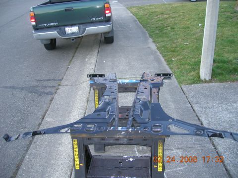 1996 Ford Bronco - Automotive frame parts are displayed on sawhorses, with a green Toyota Tundra visible in the background.