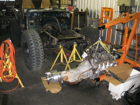 1994 Jeep YJ - A green Jeep YJ is in a workshop, with its engine being lifted out by an engine hoist.