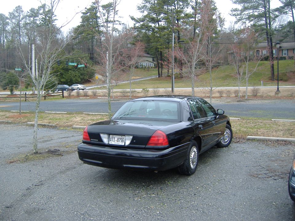 Black 2001 Ford Crown Victoria parked on gravel lot. License plate ATT-8756