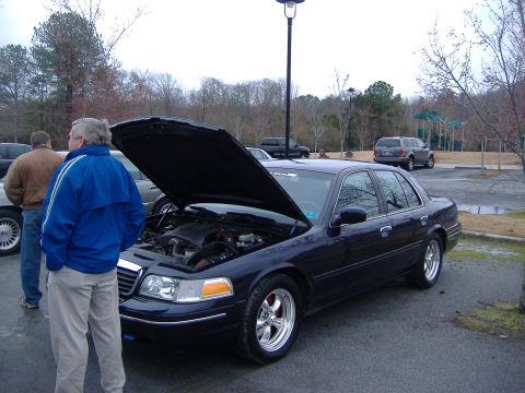 2001 Ford Crown Victoria - A dark blue 2001 Ford Crown Victoria is parked with its hood up, revealing the engine compartment.