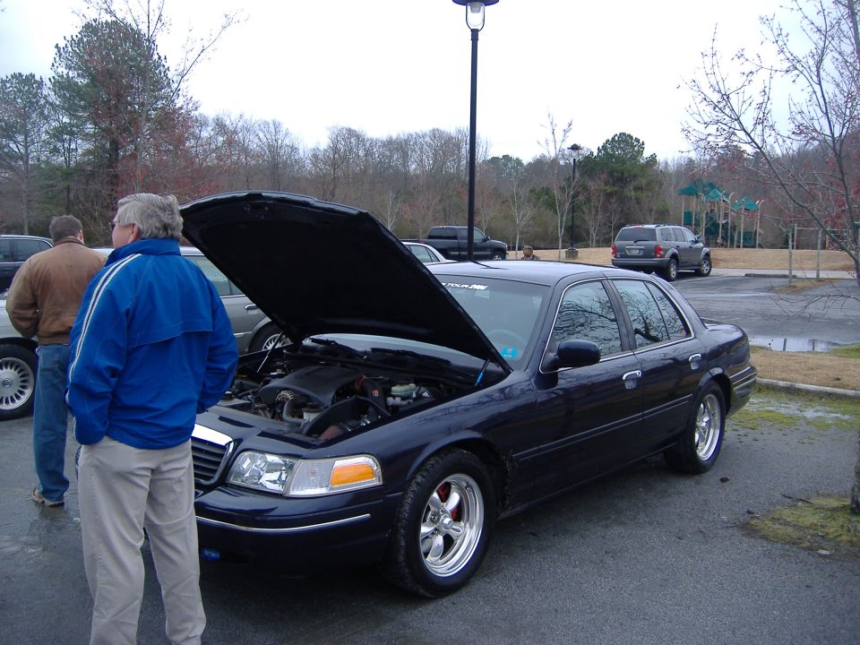Dark blue 2001 Ford Crown Victoria with hood open, showing engine. Two men standing nearby
