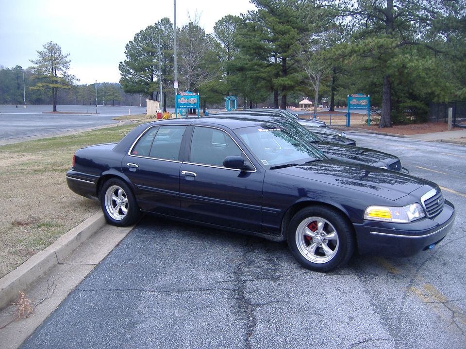 Dark blue 2001 Ford Crown Victoria parked curbside, showing its front quarter panel and side profile with aftermarket wheels