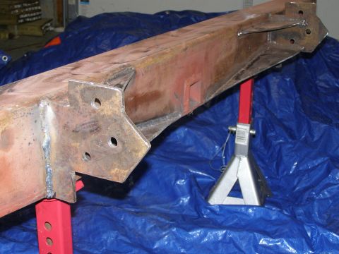 1993 Ford Bronco - A heavily rusted metal beam, likely a frame component, is supported by jack stands on a blue tarp.