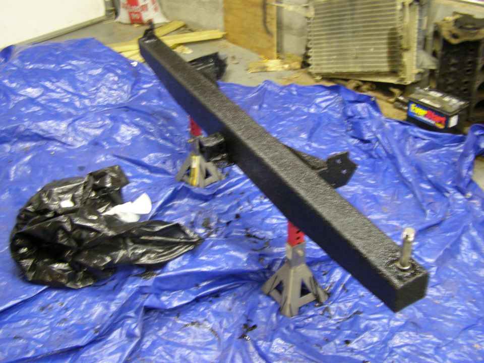 Black rear bumper and trailer hitch assembly on blue tarp