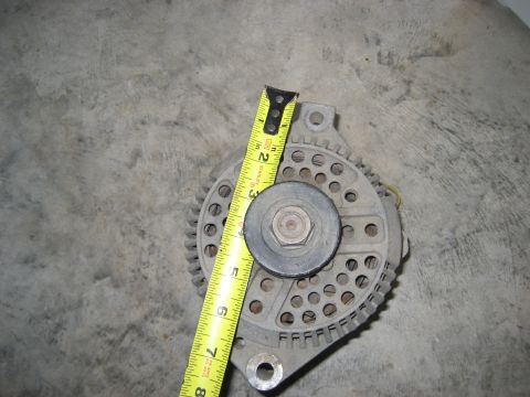 1981 Ford Bronco - Close-up of an alternator, with a tape measure providing a sense of scale.