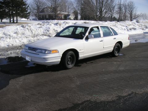 1997 Ford Crown Victoria - A white 1997 Ford Crown Victoria is parked on a road with snow on the ground.