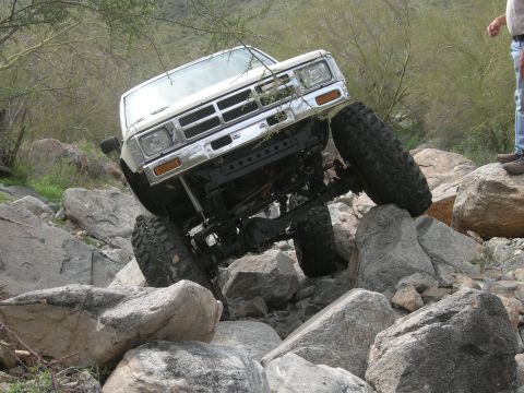 1986 Toyota Hilux - This off-road vehicle navigates a rocky terrain, its front end angled upwards.
