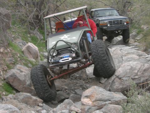 1986 Toyota Hilux - Two vehicles traverse a challenging rocky trail, with the lead buggy at a steep angle.