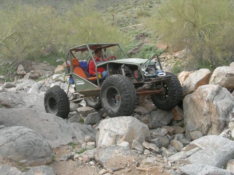 1986 Toyota Hilux - A custom off-road buggy tackles a challenging rocky trail in a desert environment.