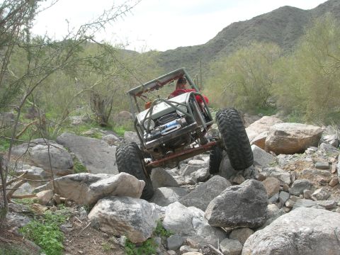 1986 Toyota Hilux - A custom off-road buggy navigates a challenging rocky trail in a desert landscape.