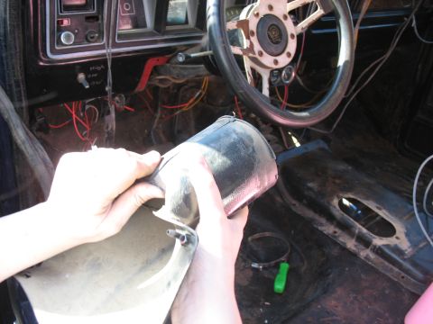 1978 Ford Bronco - Hands manipulate a black steering column cover inside a 1978 Ford Bronco, revealing exposed wiring and a worn interior.