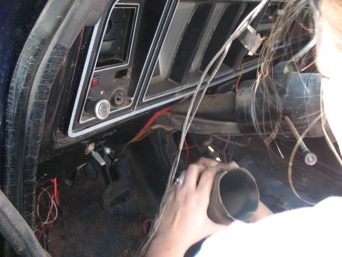 1978 Ford Bronco - The interior of a 1978 Ford Bronco shows the dashboard, steering column, and pedals, with a person's hands working on a part.