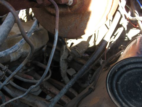 1978 Ford Bronco - Engine bay components including hoses, wires, and rusty metal parts are visible in this close-up shot.