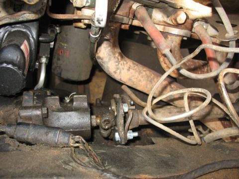 1978 Ford Bronco - Close-up view of steering column parts, including a gearbox and U-joint, with surrounding engine components.